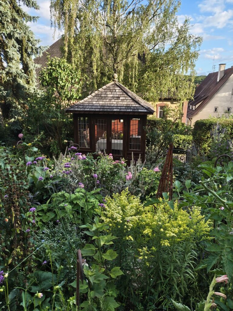 Gartenpavillon, versteckt hinter einem Hochstaudenbeet