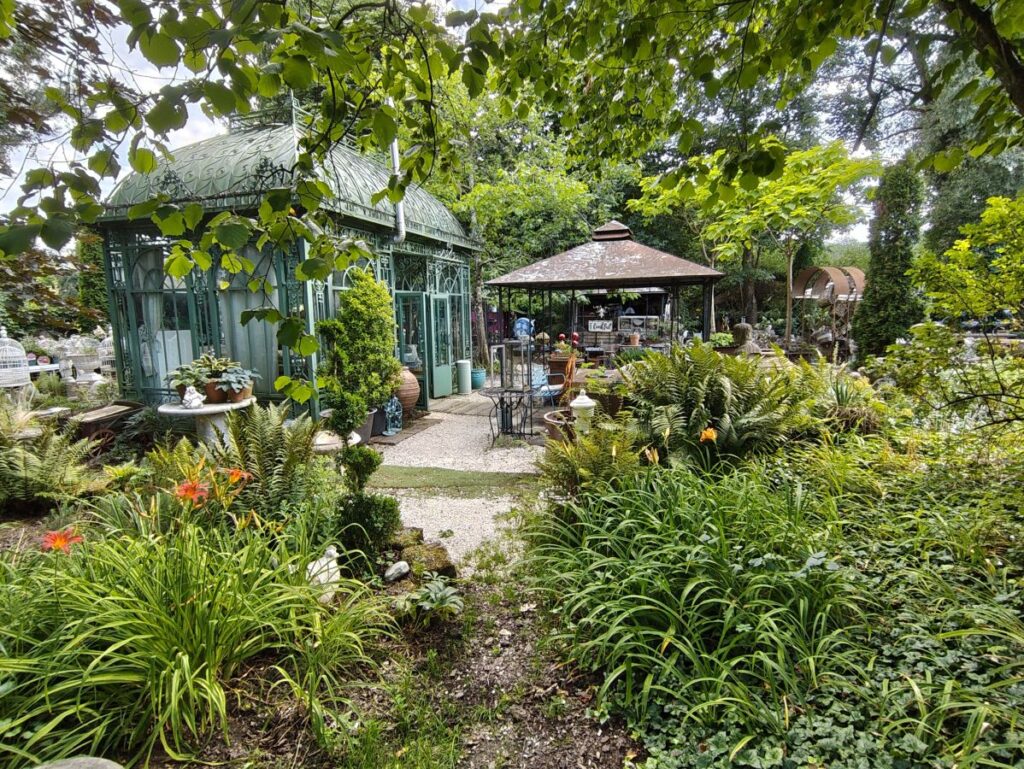 Garten mit Taglilien und Farnen vor einem Gartenpavillon